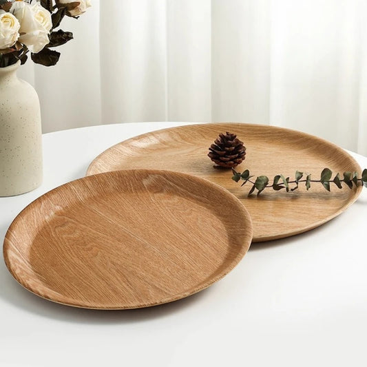 Two wooden plates on a white surface with a vase of flowers in the background.