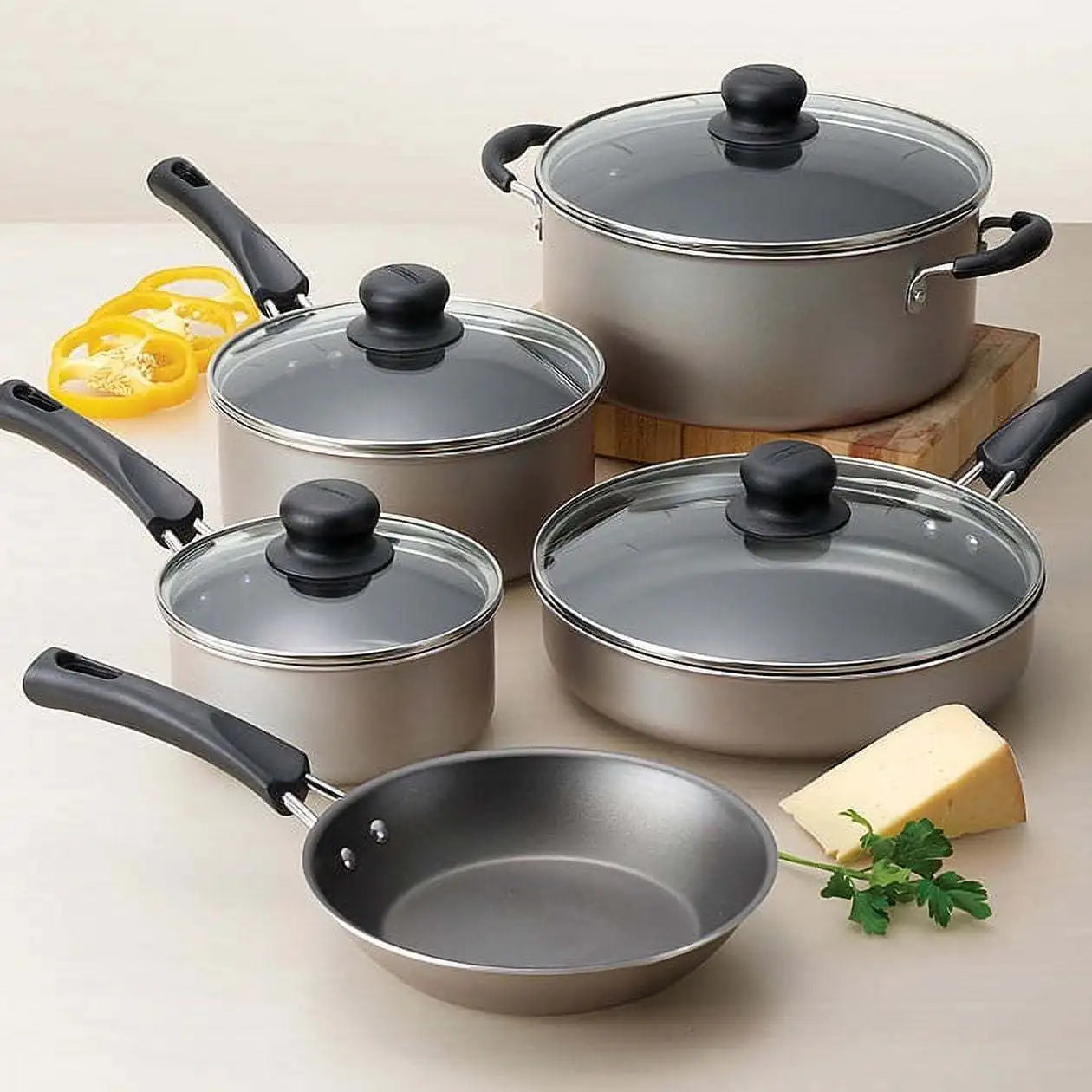 Set of stainless steel cookware with black handles on a light background