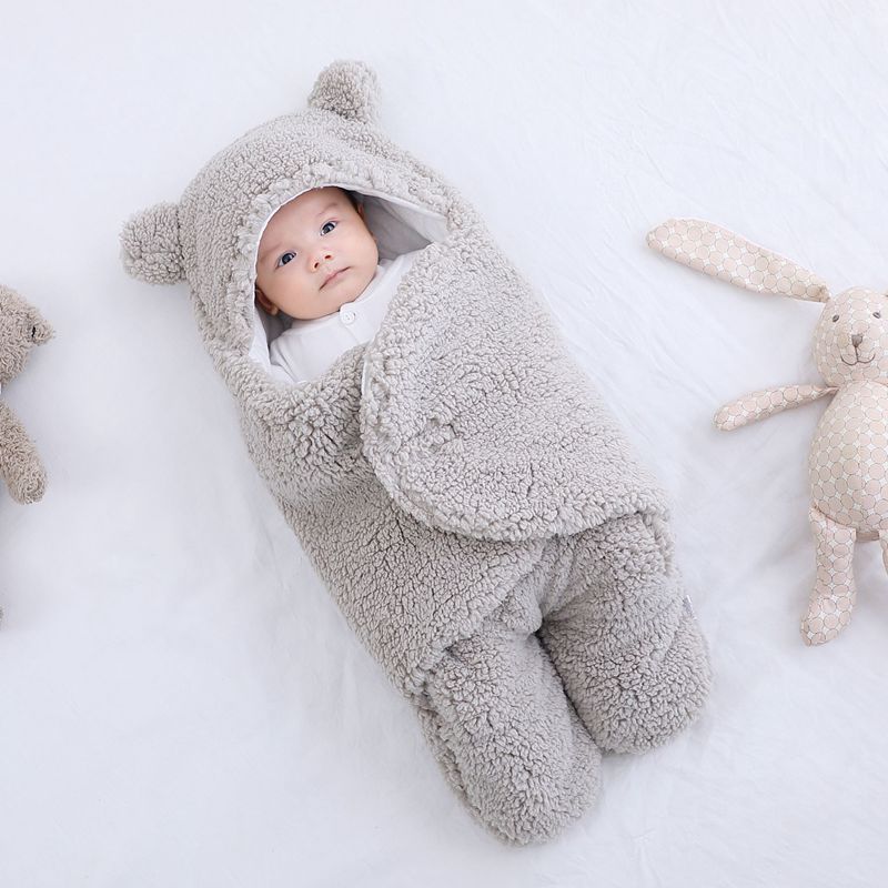 Baby in a gray fleece onesie with bear ears on a white background