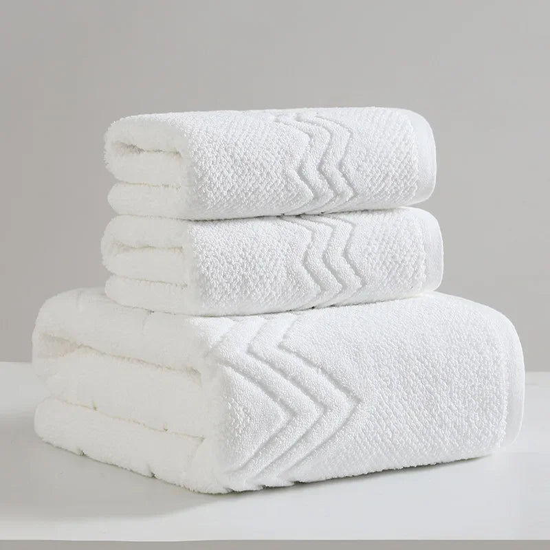 Stack of white towels with a subtle pattern on a gray background