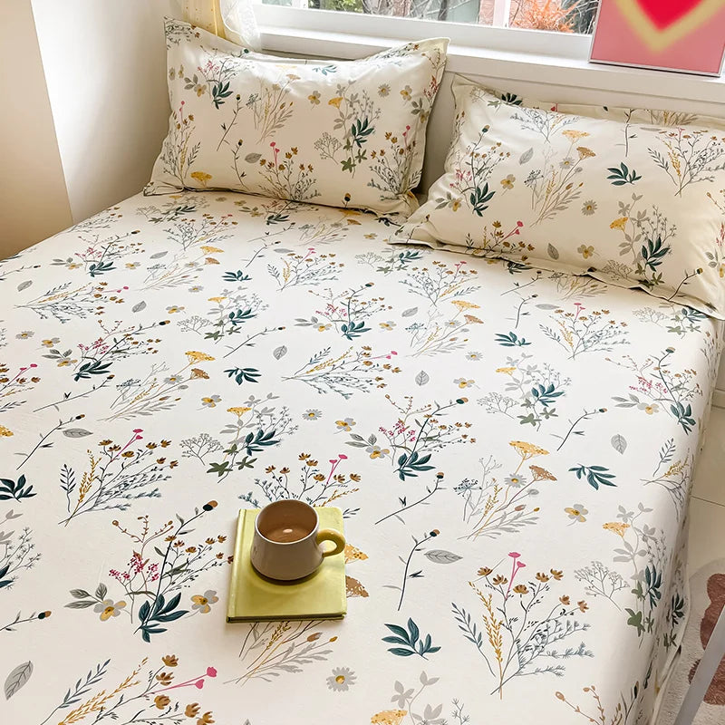 Floral patterned bedding set on a bed with a cup and book.