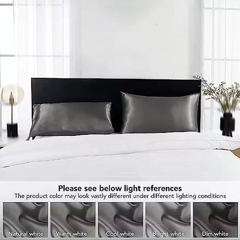 Black satin pillowcases on a bed with light background