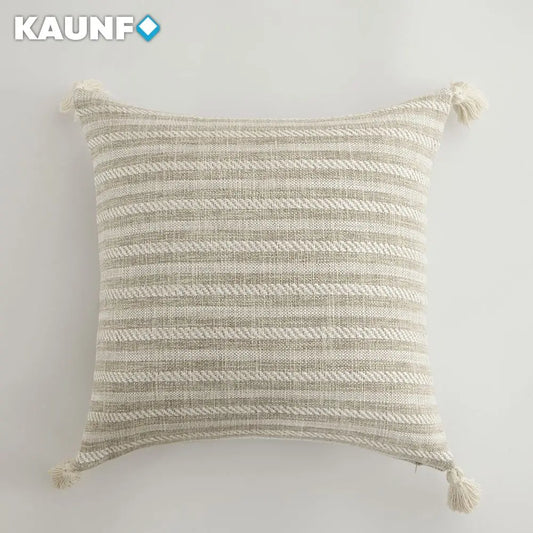Textured pillow with tassels on a light gray background, featuring the brand 'KAUNF'.