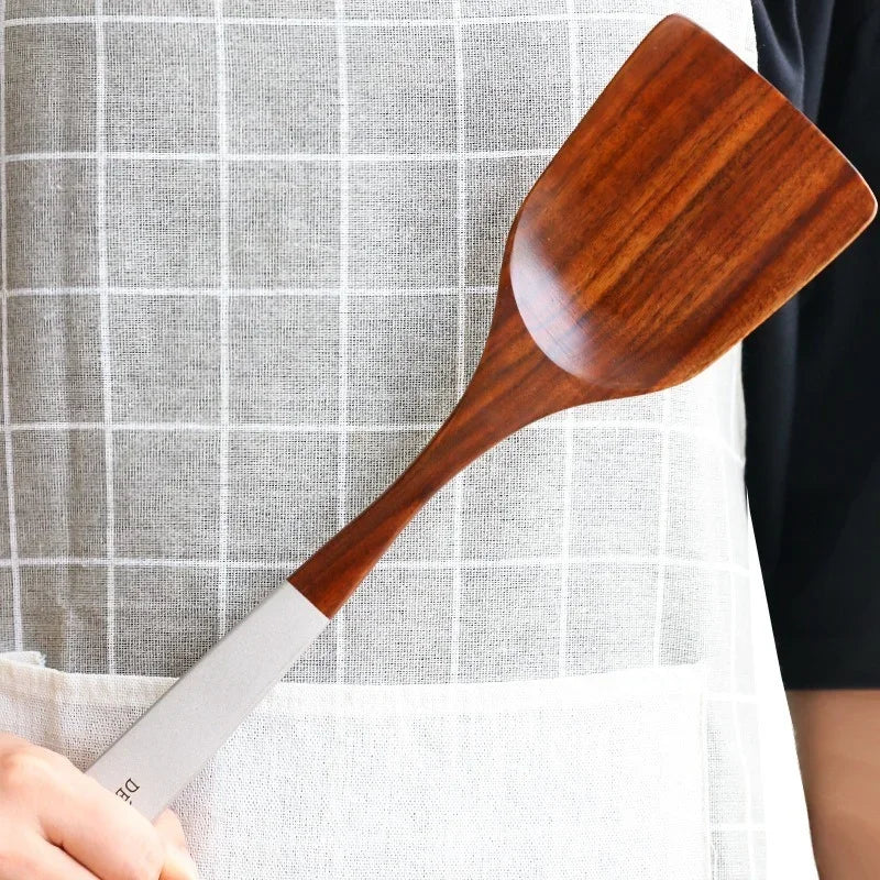 Wooden spatula held by a person against a checkered background