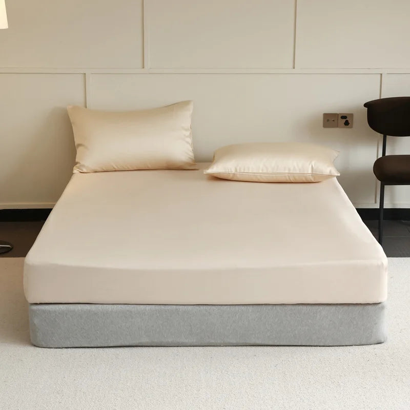 Beige mattress with pillows on a bed frame against a white wall.