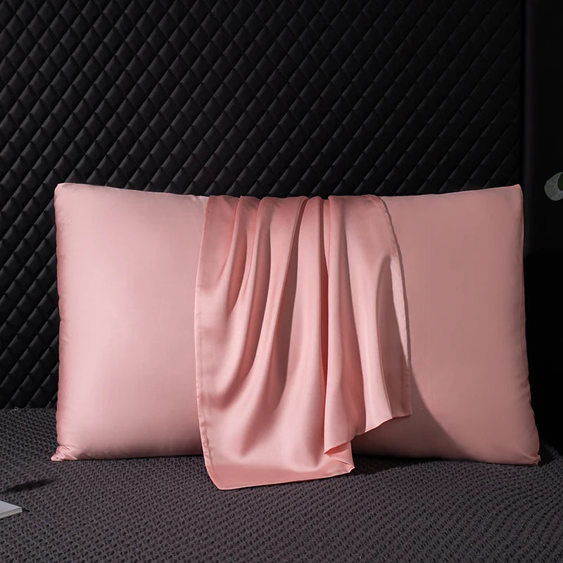Pink satin pillowcase on a textured black surface
