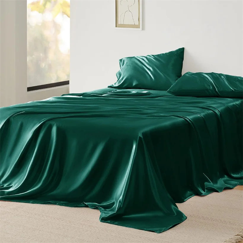 Green satin sheet set on a bed in a bright bedroom.