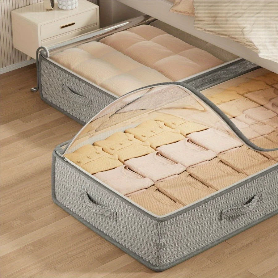 Gray storage box with transparent lid containing folded clothes on a wooden floor.