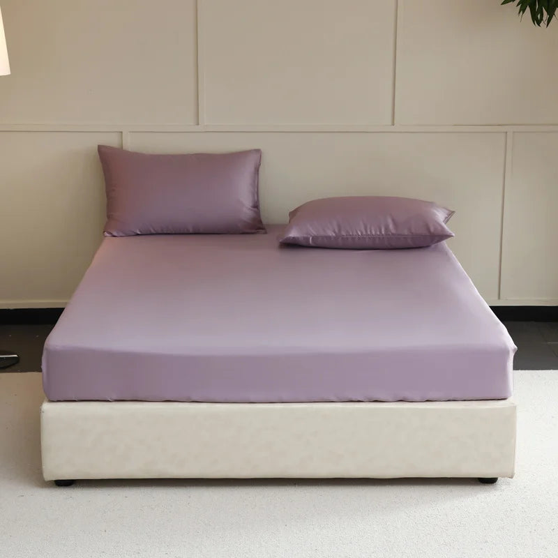 Bed with purple bedding and pillows in a minimalistic room.