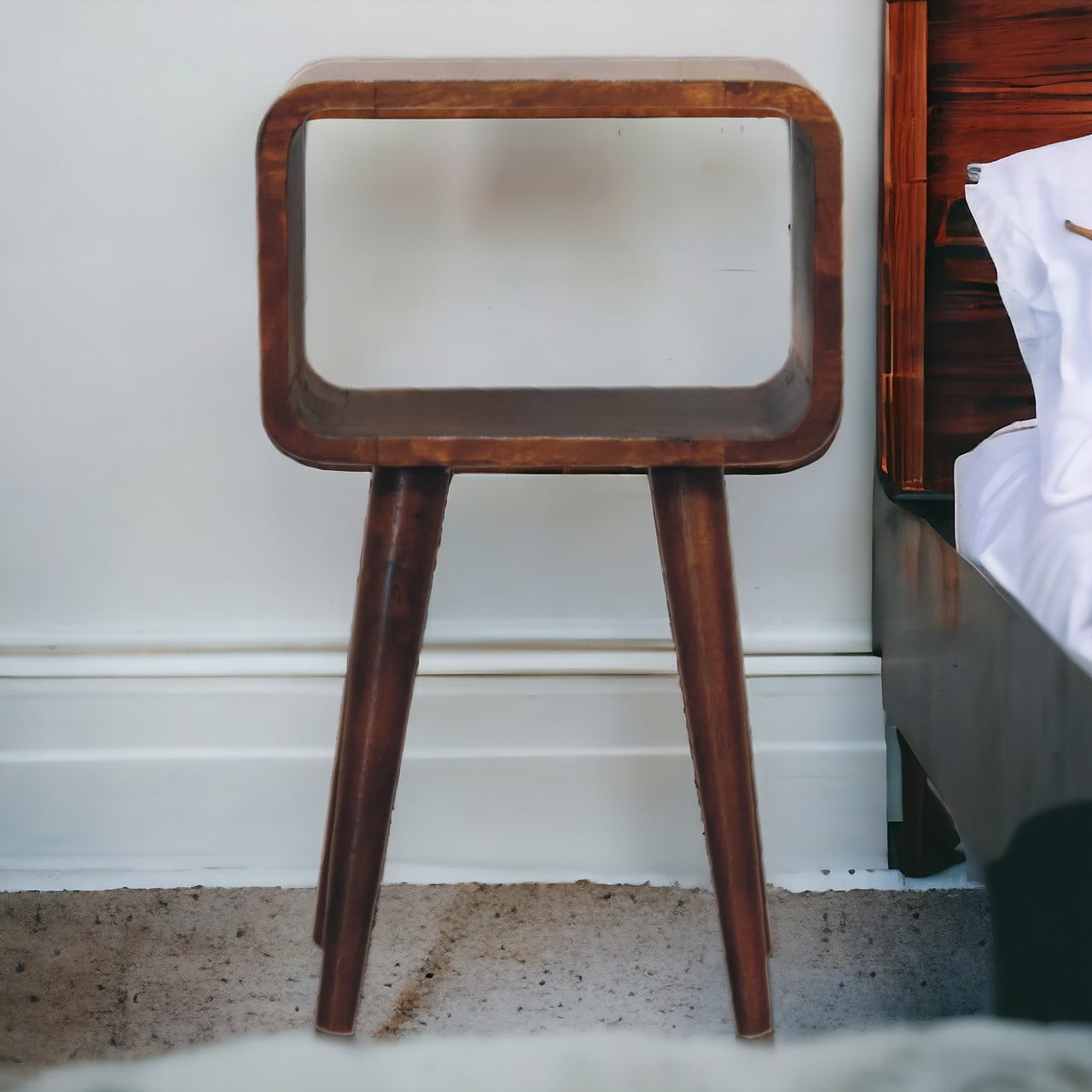 Mini Chestnut Open Nightstand made from solid mango wood with four tapered legs and one open storage compartment, At a bedside