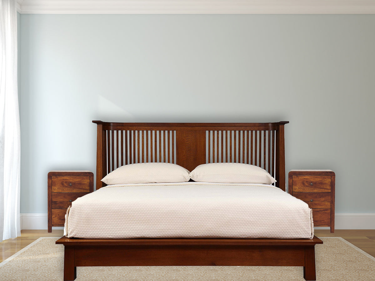 Naya Chestnut Nightstand made from solid mango wood with three drawers and brass knobs. View of a bed with two Naya nightstand on each side