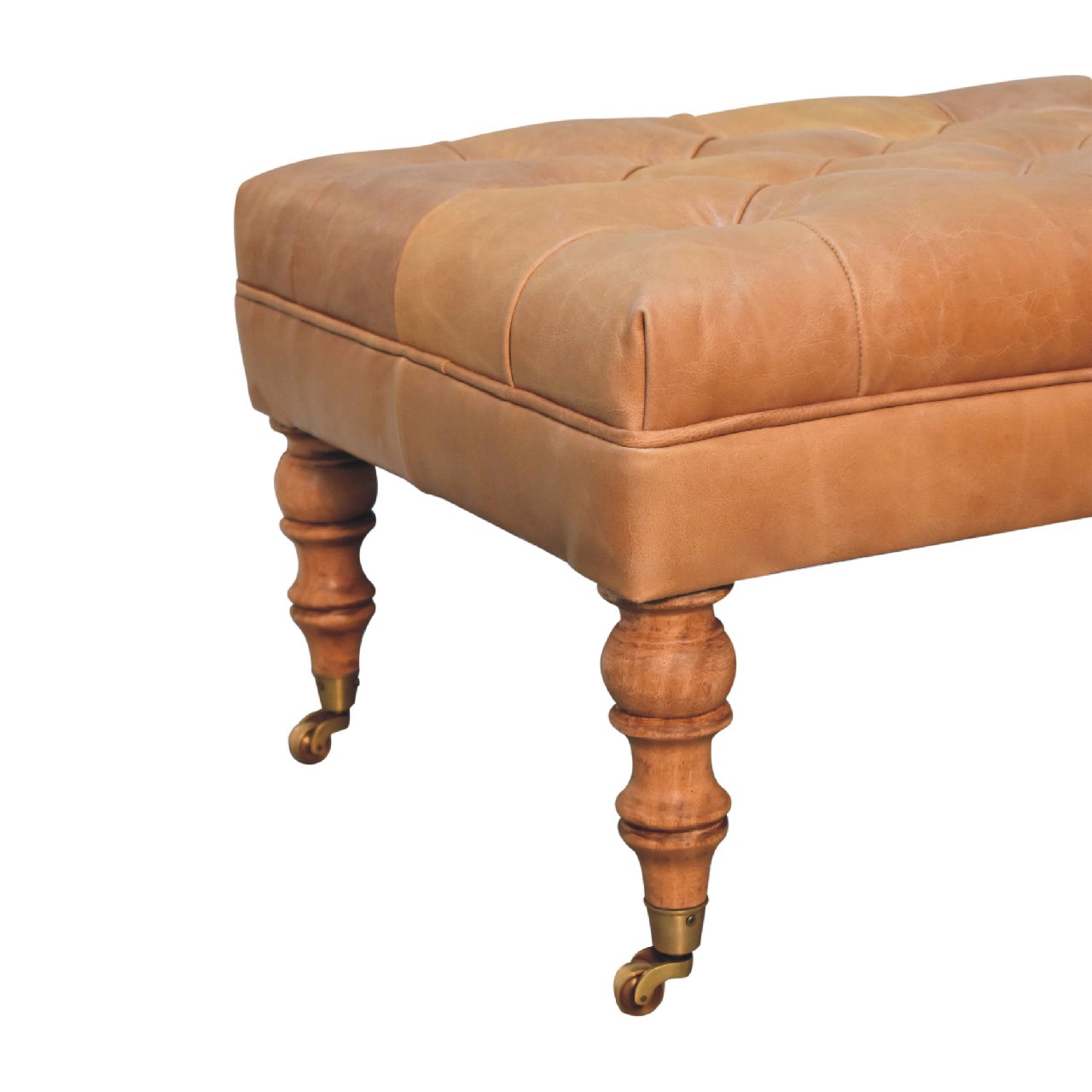Tan buffalo leather ottoman with solid mango wood base, deep-buttoned top, and light walnut hand-turned feet. Leg view