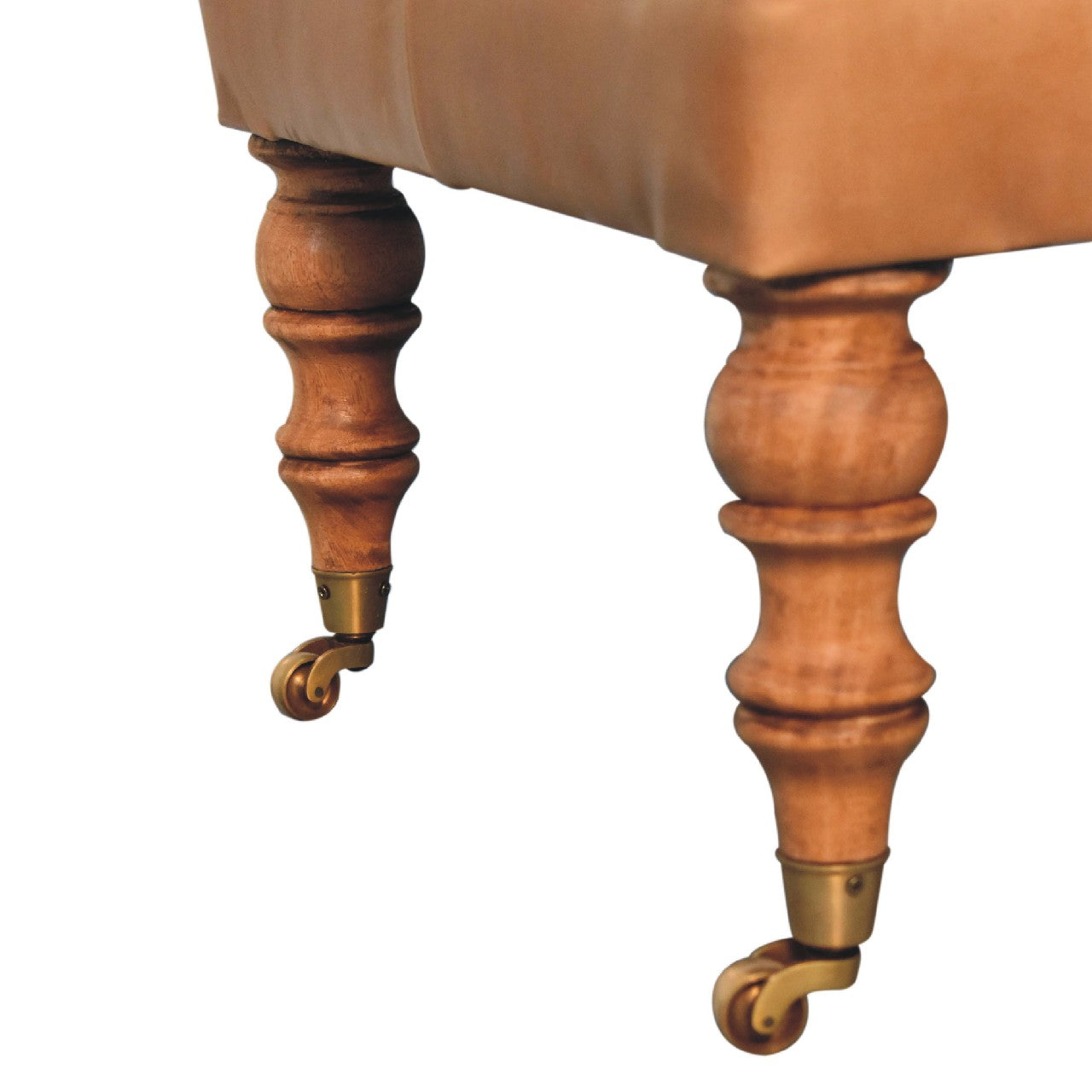 Tan buffalo leather ottoman with solid mango wood base, deep-buttoned top, and light walnut hand-turned feet. Leg view