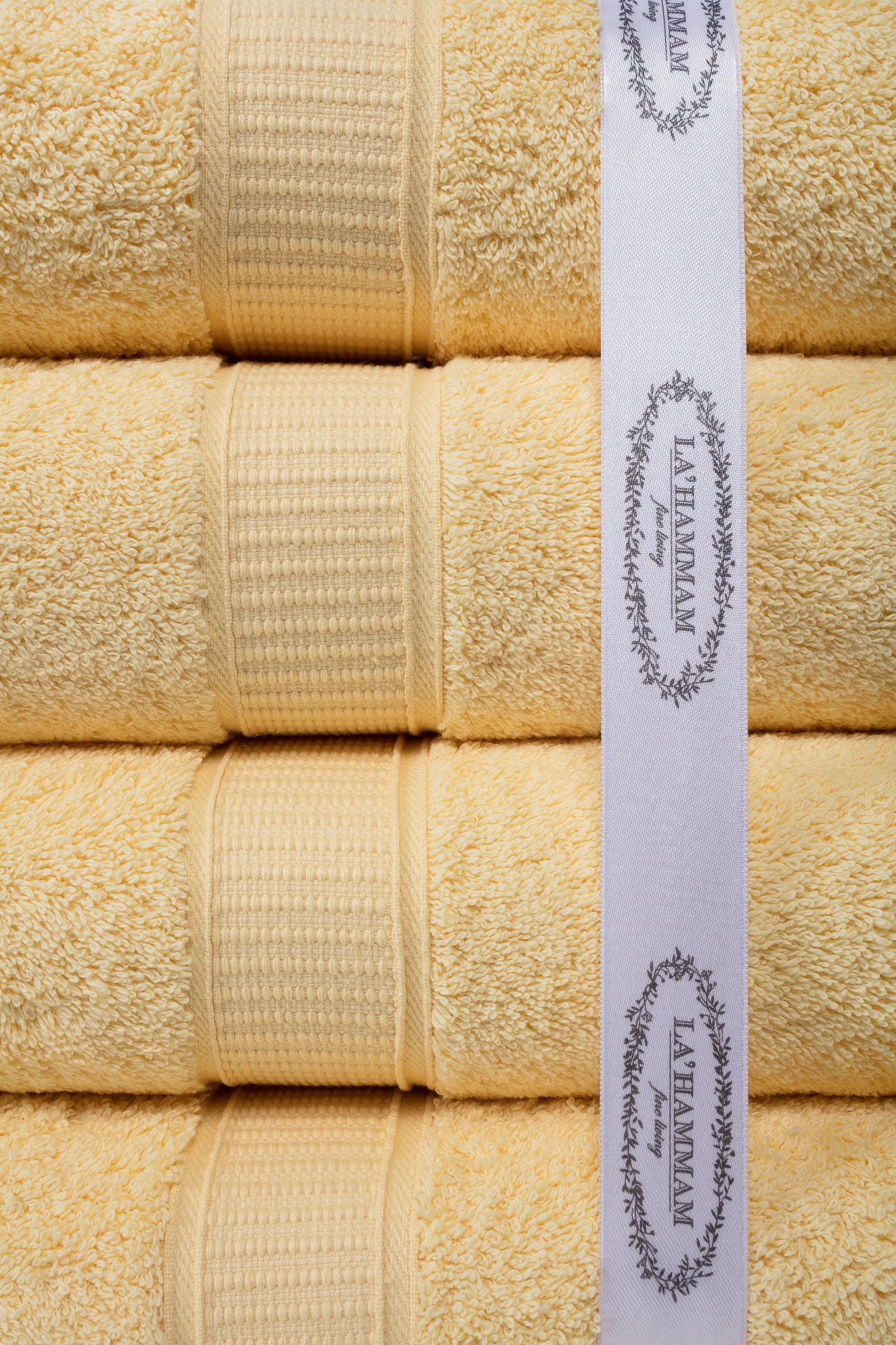 Stack of beige towels with a Lusham label on a white background