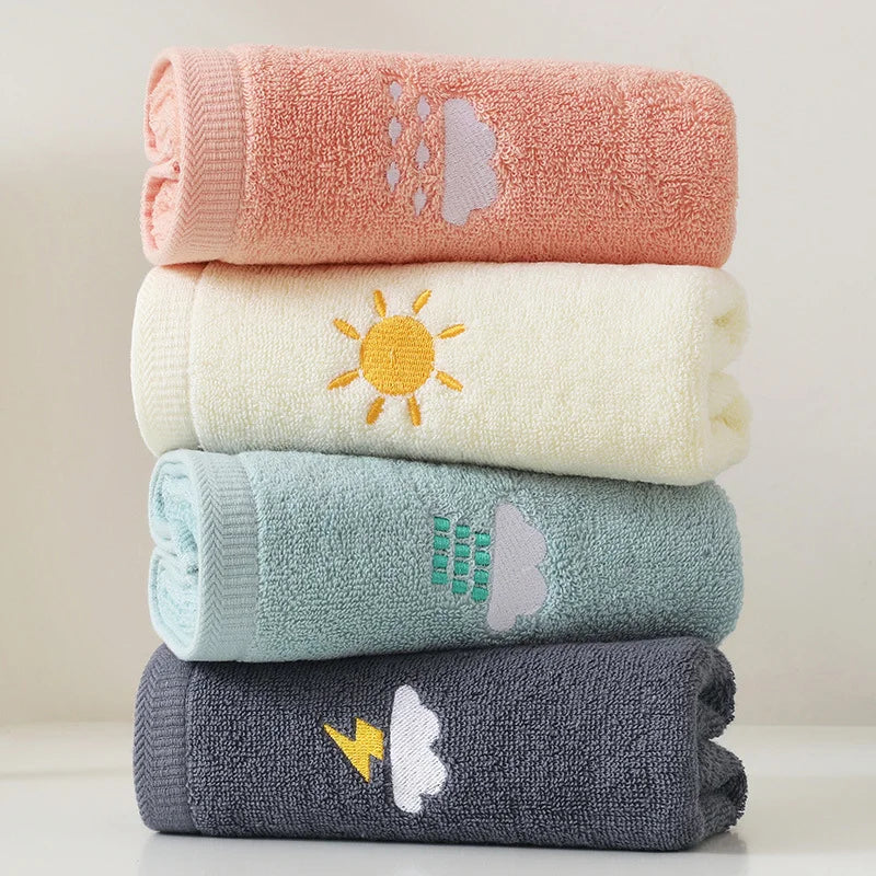 Stack of four colorful towels with embroidered designs on a light background