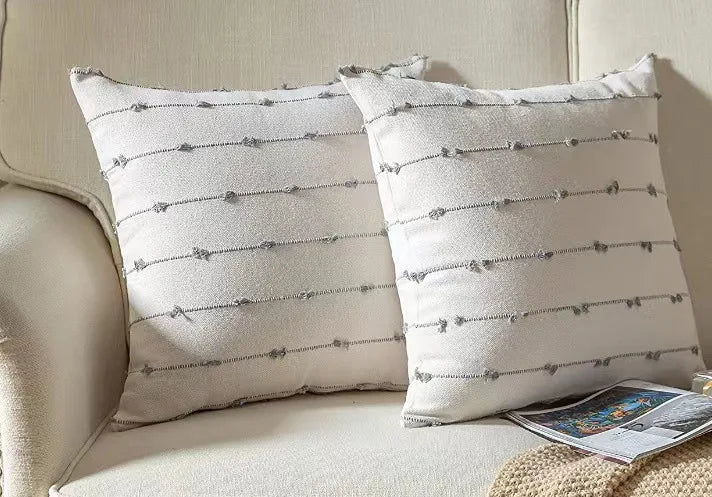 Two decorative pillows on a beige sofa with a newspaper.