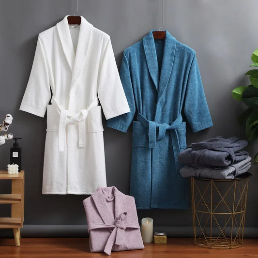 White, blue, and pink bathrobes hanging and folded against a gray wall with decorative items.