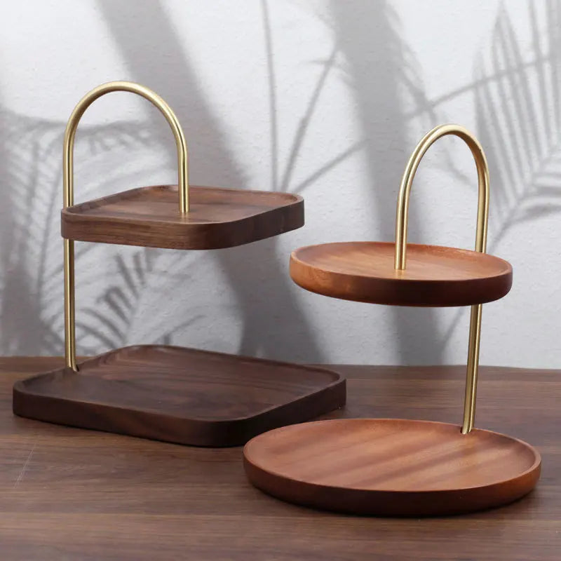 Wooden tiered trays with gold metal stands on a wooden surface.