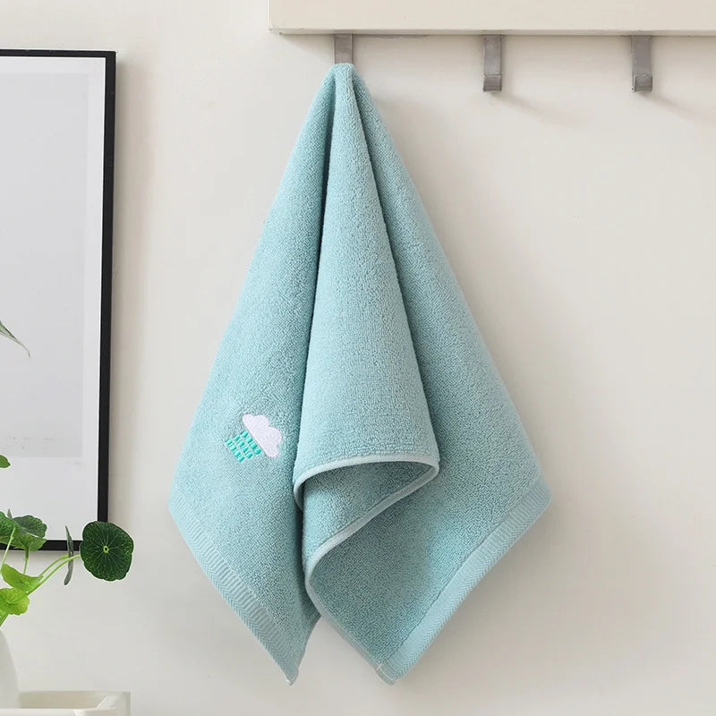 Light blue towel with a cloud design hanging on a rack against a white wall.