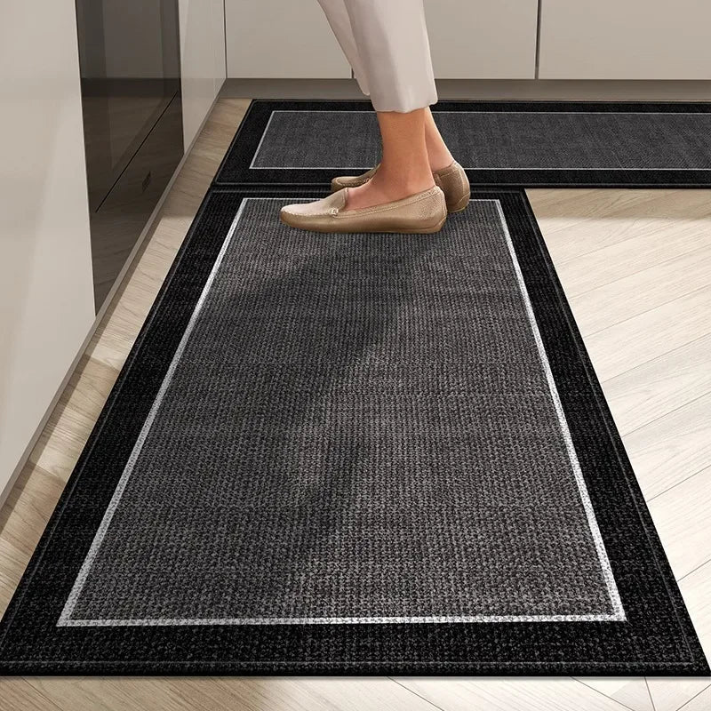 Person stepping onto a black doormat with a white border in a home setting.