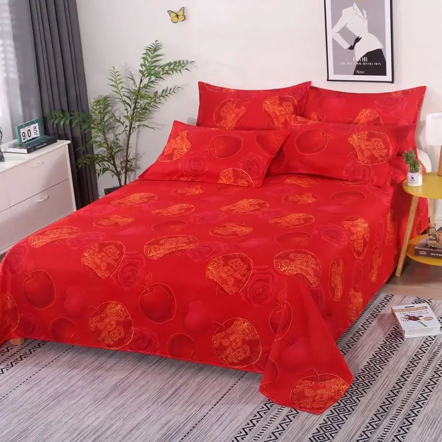 Red patterned bedspread on a bed in a bedroom setting with decor elements.