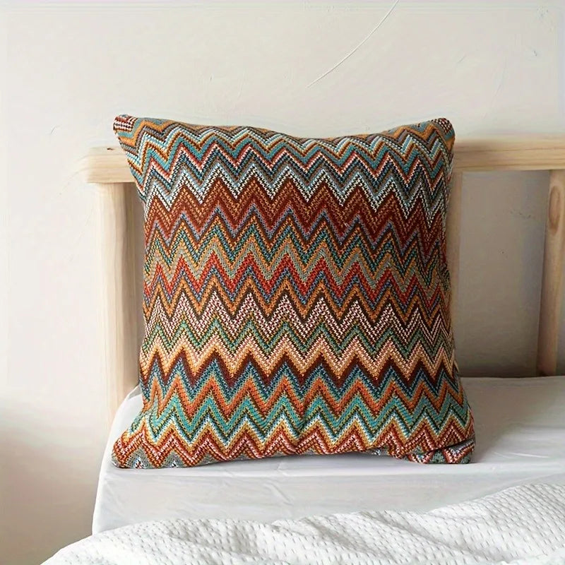 Colorful zigzag patterned pillow on a bed with a white background