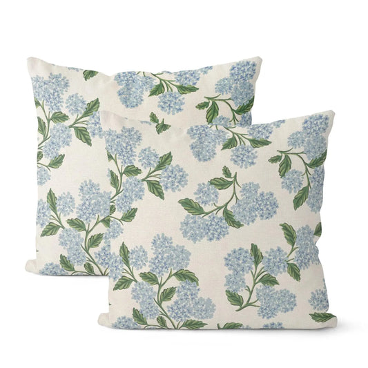 Two floral-patterned pillows with blue flowers and green leaves on a white background