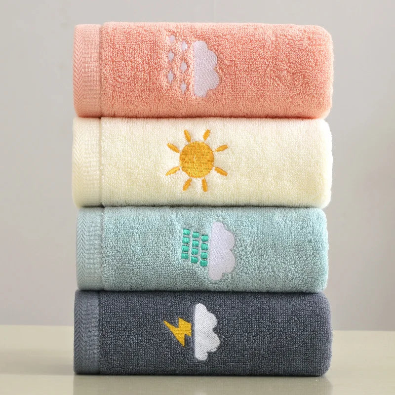 Stack of four colorful towels with embroidered designs on a neutral background