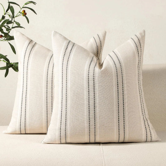 Two striped pillows on a sofa with a neutral background