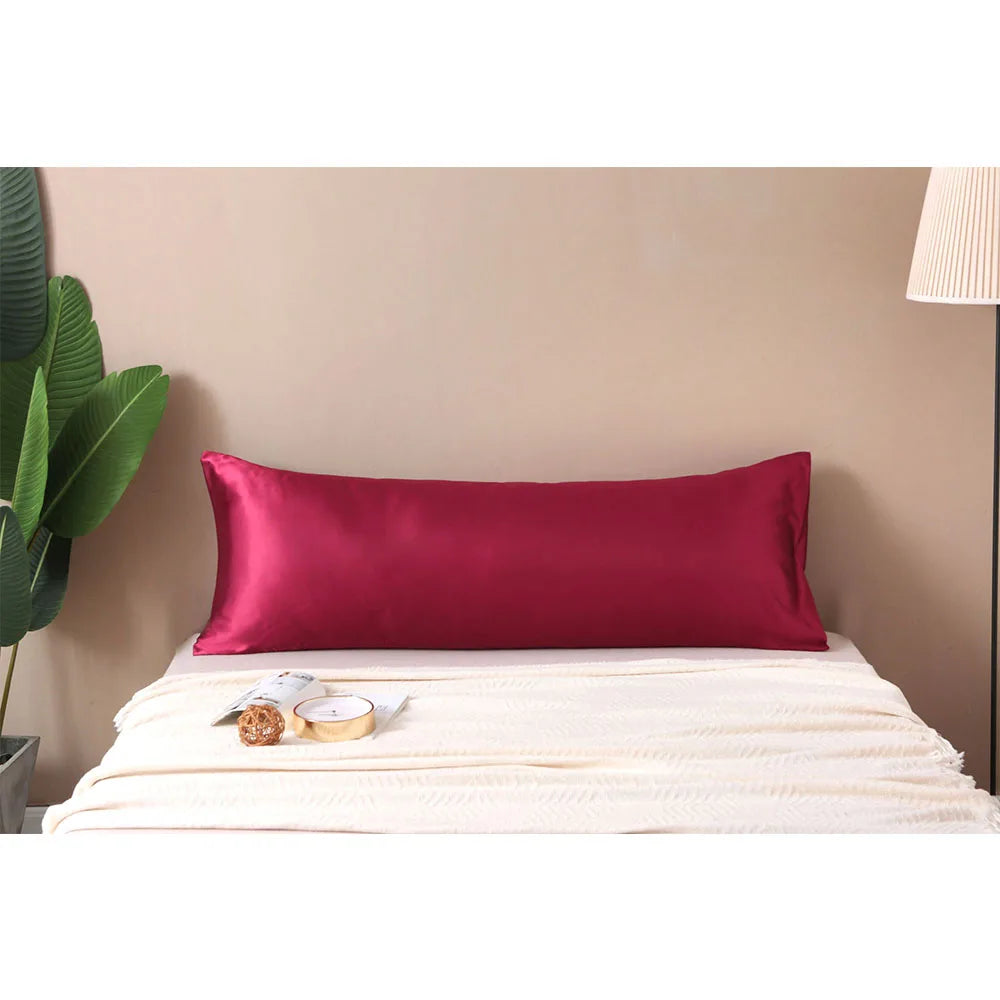 Red satin pillow on a bed with a neutral background