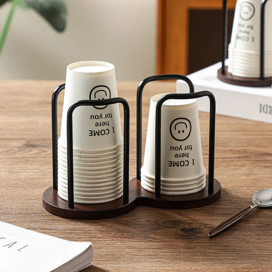 Stack of white cups with text in a black holder on a wooden surface.