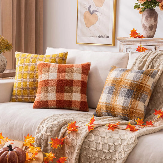 Decorative pillows and blanket on a sofa with autumn-themed decor.