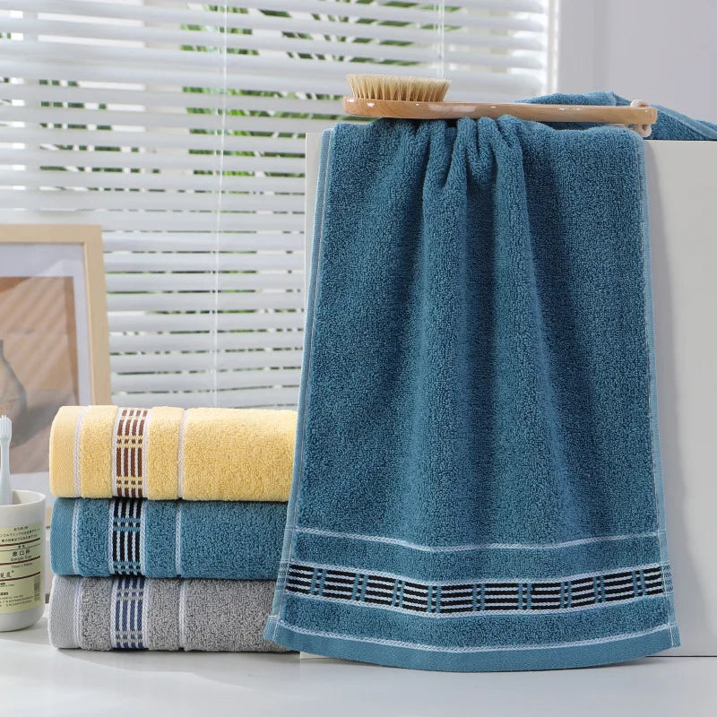Stack of blue towels with a yellow towel on a white surface