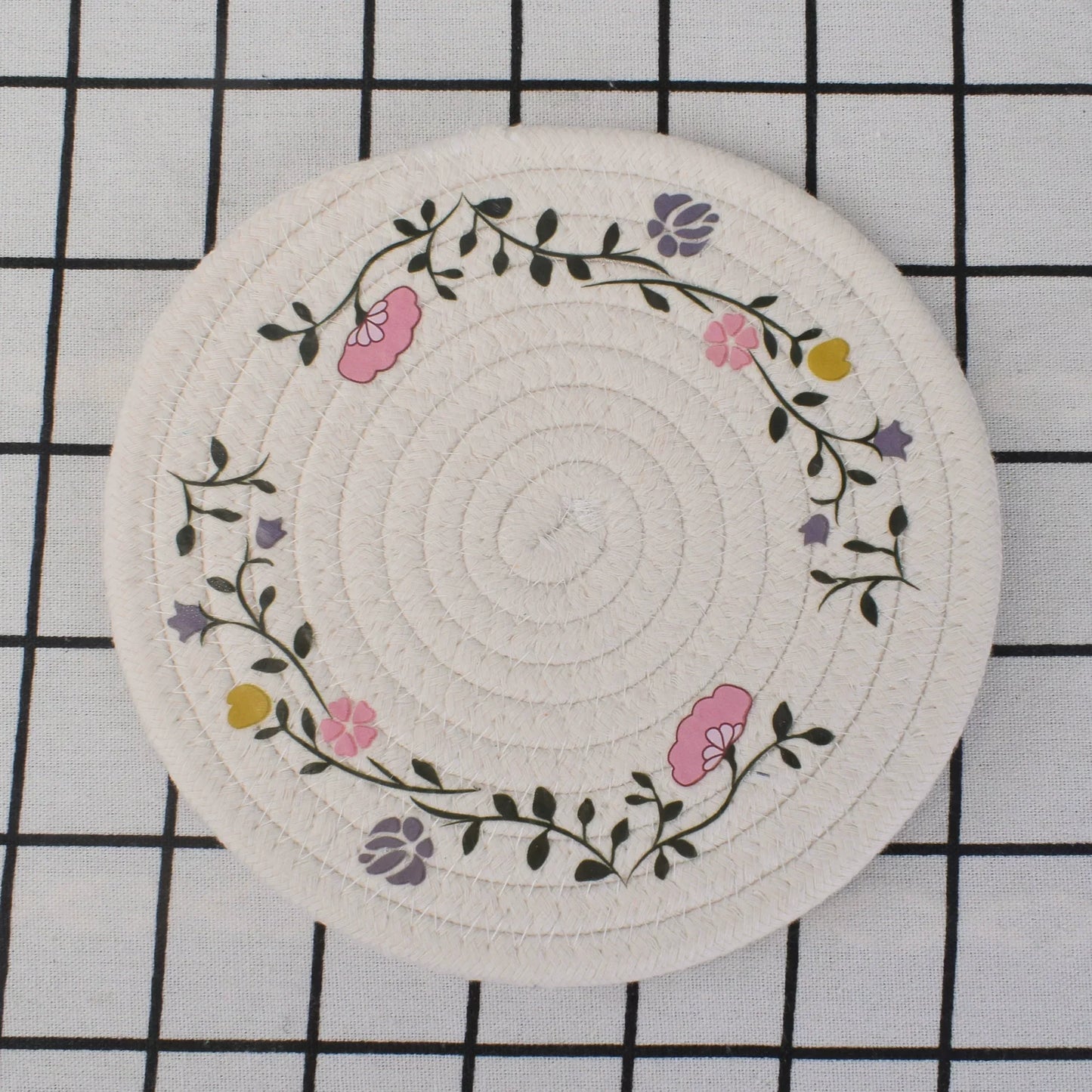 Round woven coaster with floral design on a grid background