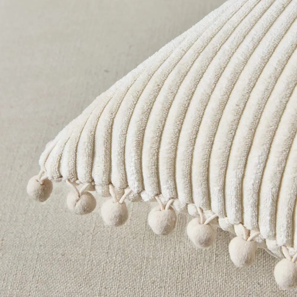 Close-up of a textured pillow with tassels on a neutral background
