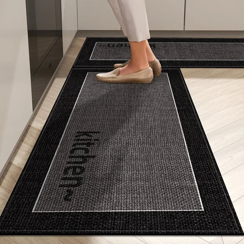 Person stepping onto a black doormat with 'kitchen' text in a home setting.