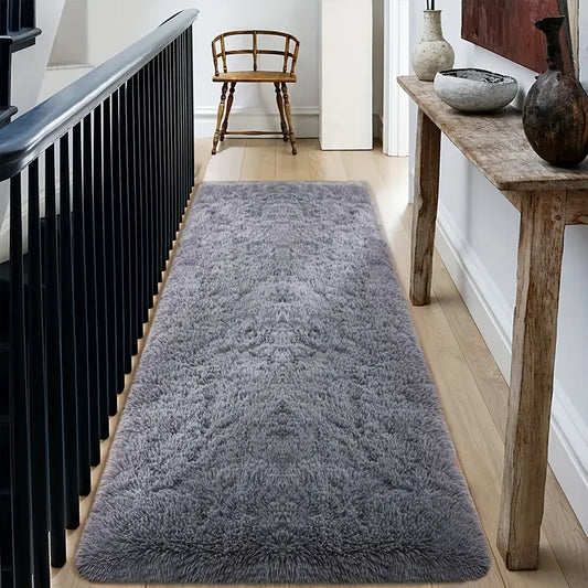 Gray runner rug on a wooden floor with a black radiator and wooden bench in the background.