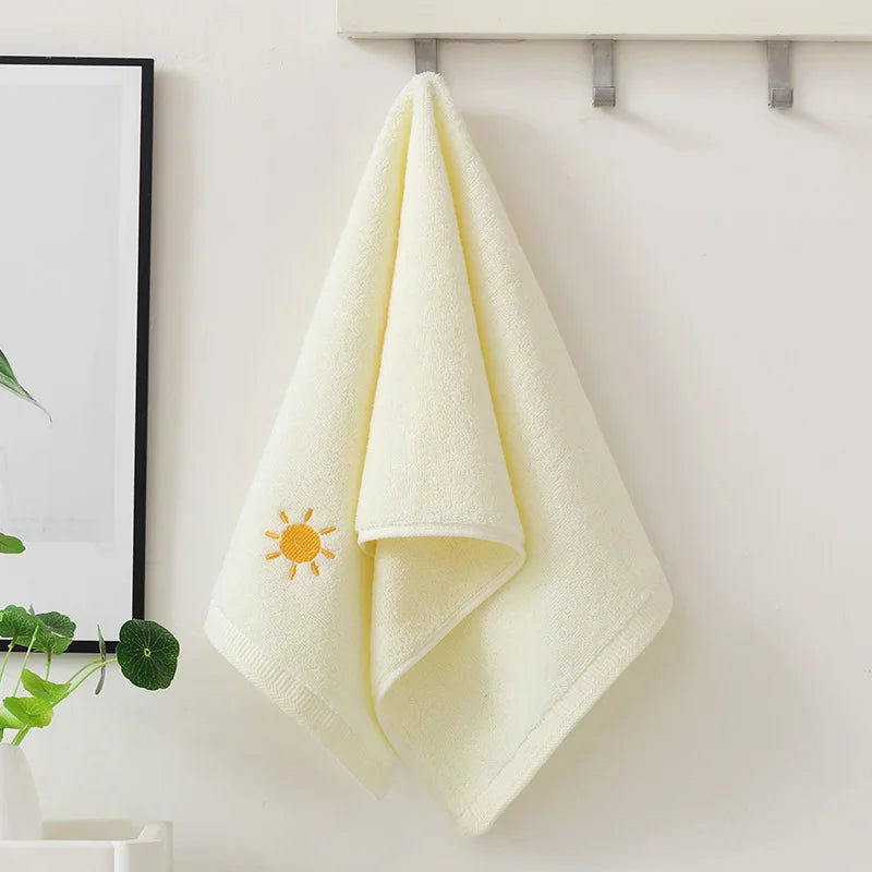 Yellow towel with a sun design hanging on a rack against a white wall.