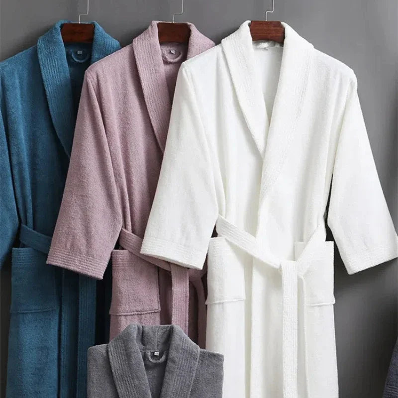 Four bathrobes in blue, pink, white, and gray hanging against a gray background.