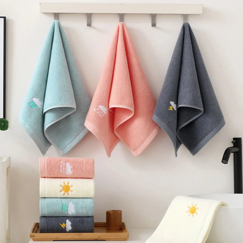 Set of colorful towels with designs hanging on a rack and stacked on a tray.