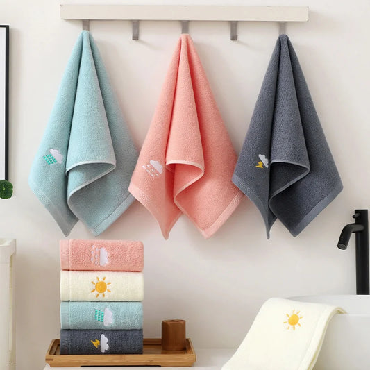 Set of colorful towels with designs hanging on a rack and stacked on a tray.