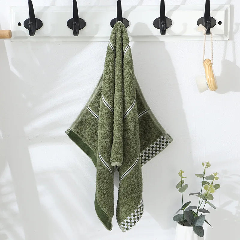 Green towel hanging on a rack with a white background