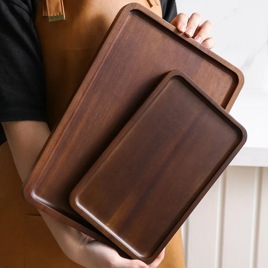 Two wooden trays held by a person against a neutral background