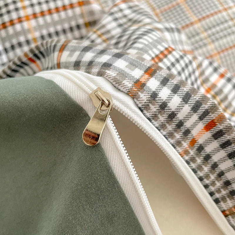 Close-up of a zipper on a green fabric with a plaid pattern in the background