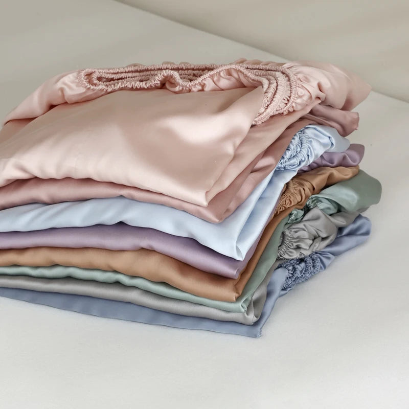 Stack of folded pastel-colored satin fabrics on a light background