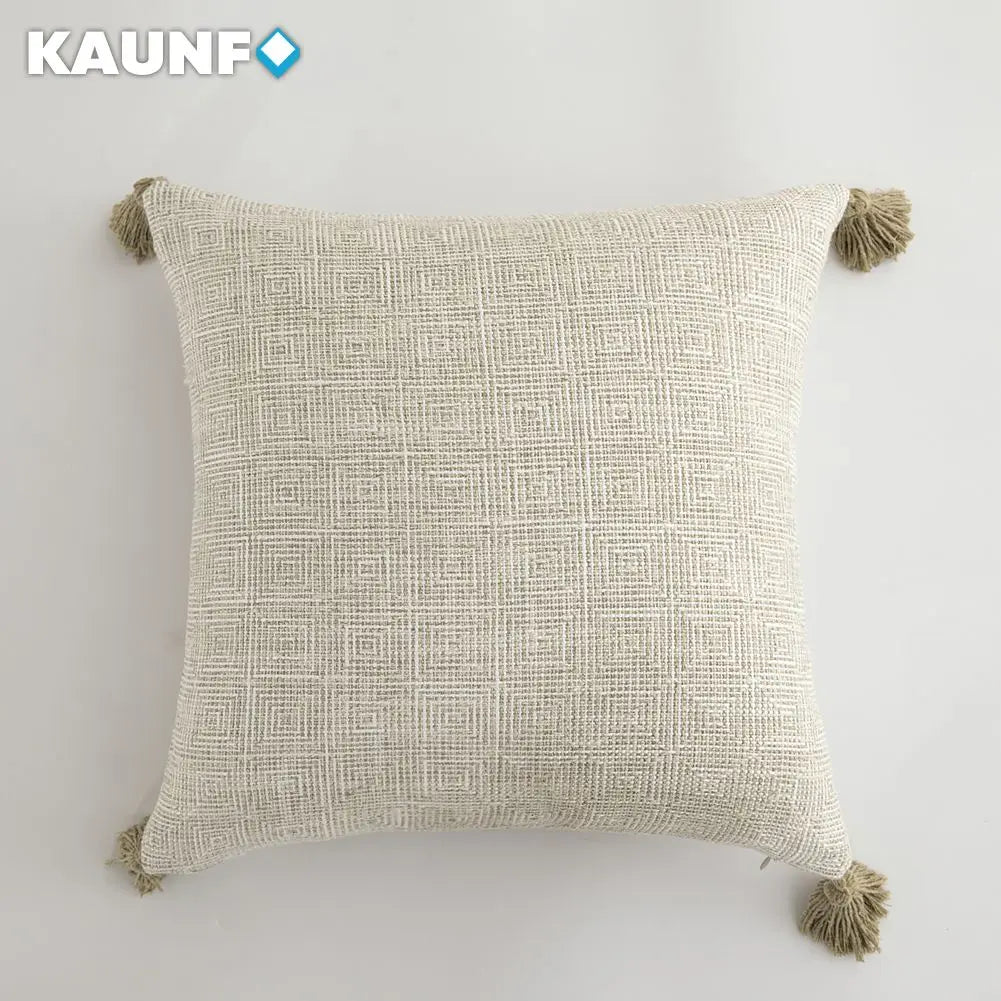 Textured pillow with tassels on a light gray background, featuring the brand 'KAUNF'.