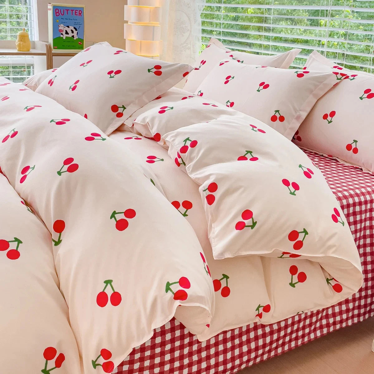 Cherry-patterned bedding set on a bed with a checkered bedspread.