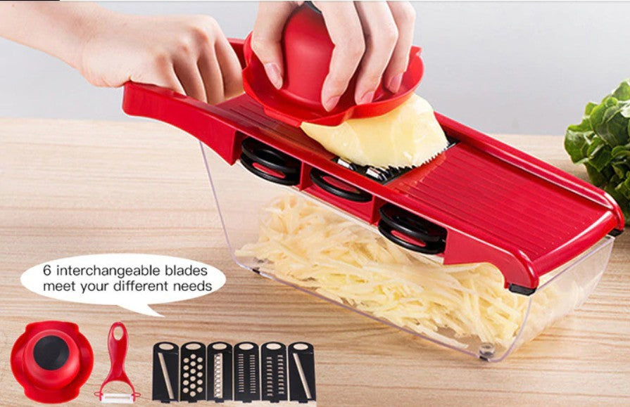 Red mandoline slicer with interchangeable blades on a wooden surface