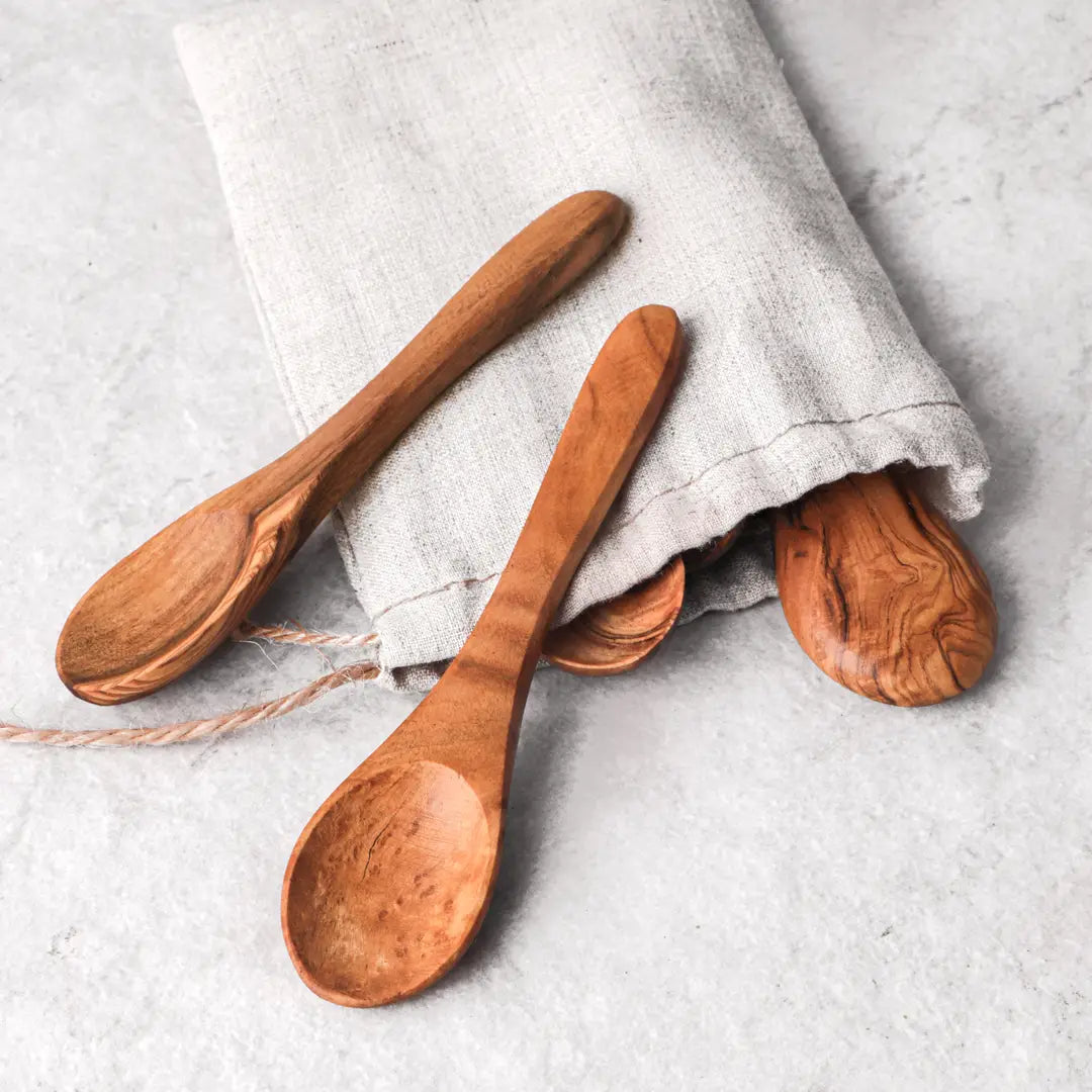 Three wooden spoons on a light gray surface with a white cloth.