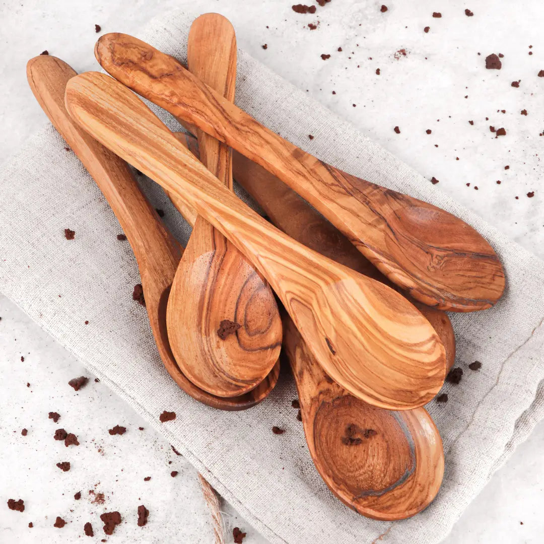 Set of wooden spoons on a textured surface with small dark particles.